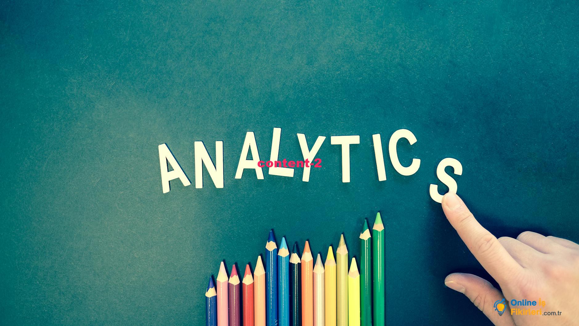 Colored pencils and letters spelling "ANALYTICS" on a textured background with a hand.