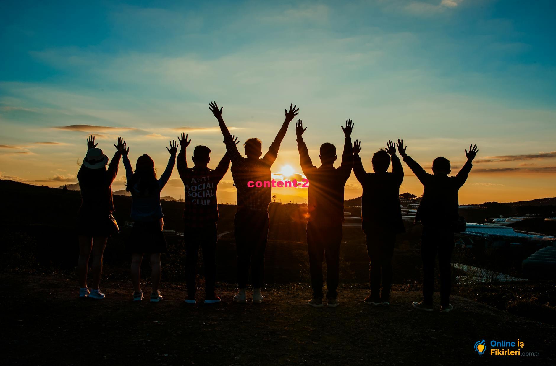 A diverse group of friends raises their arms in celebration against a vibrant sunset backdrop.