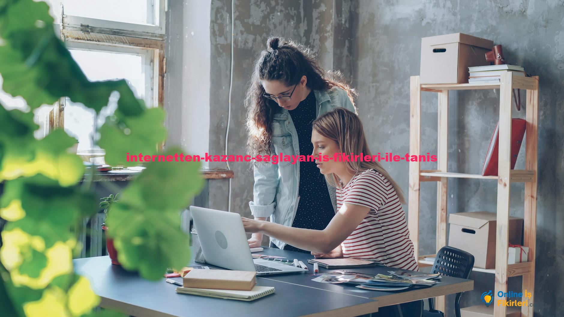 Two young women working together in a modern office with a laptop and plants.